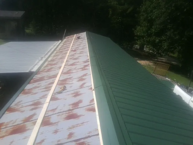Old rusted panels beside newly installed green metal roofing — Wind Damage Roof Repair by Roofing Brothers in Gunpowder