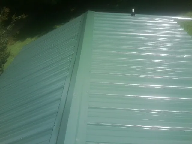 New green metal panels meeting at the ridge of a roof — Flat Roof Repair work by our crew in Gunpowder