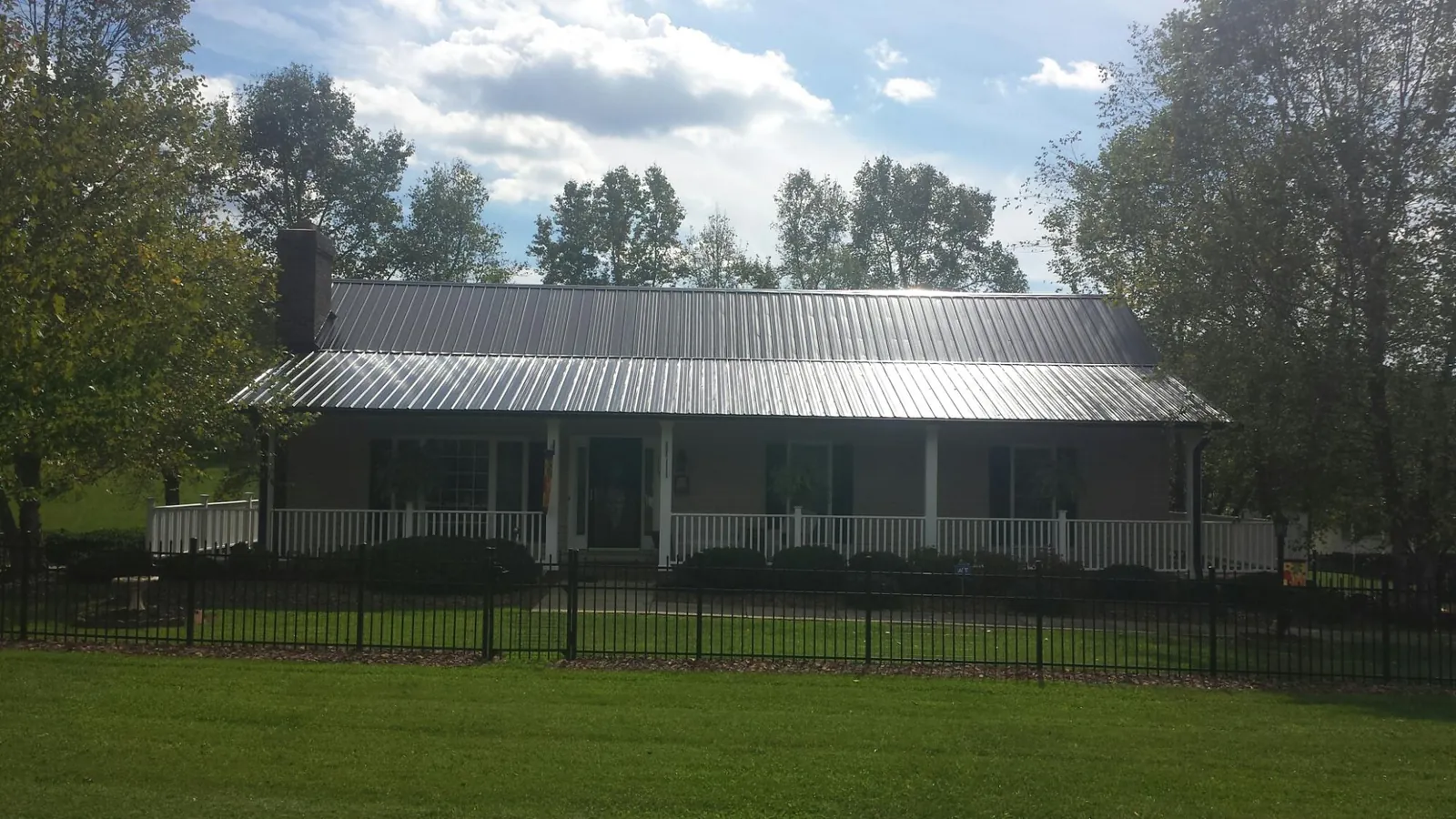 Gray metal roof on a brick ranch with a full width front porch — Gutter Guard Installation work by our crew in Gunpowder